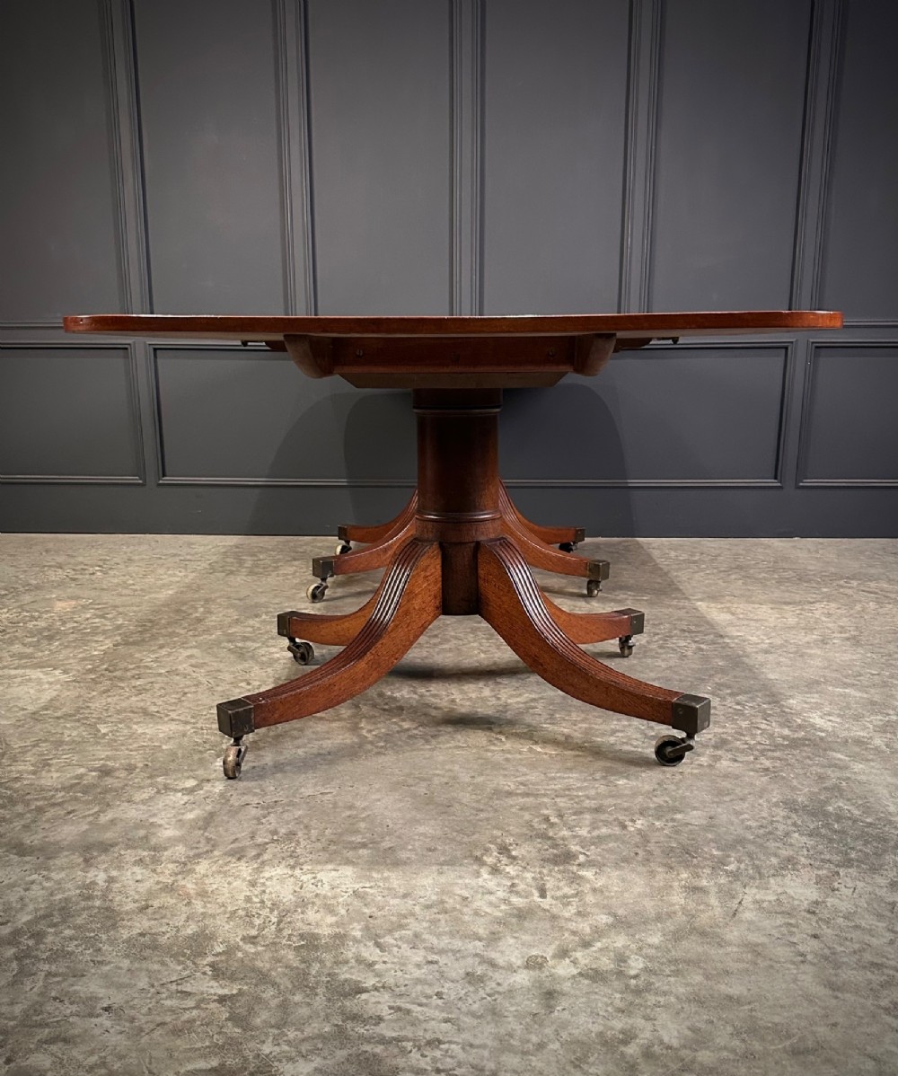 An extended mahogany twin pillar dining table with reeded splayed legs and brass castors. View XIII