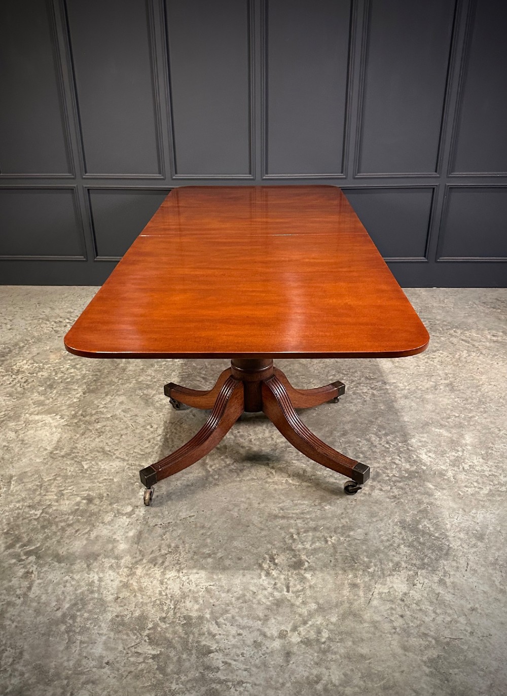 An extended mahogany twin pillar dining table with reeded splayed legs and brass castors. View XIV