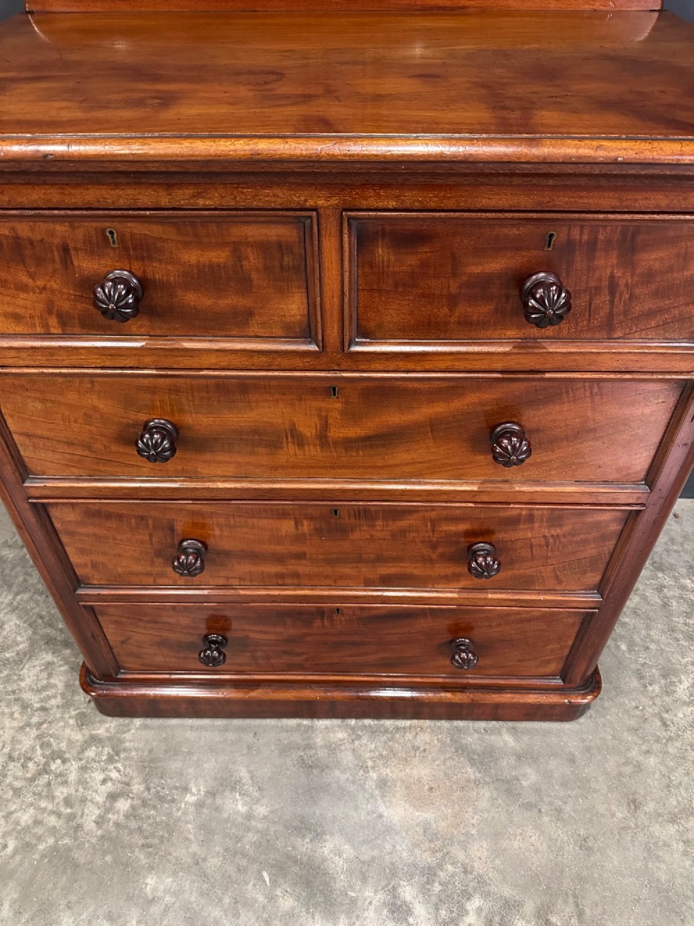 A Victorian flame mahogany chest of drawers featuring two short over three long drawers with turned knobs and a plinth base. View V