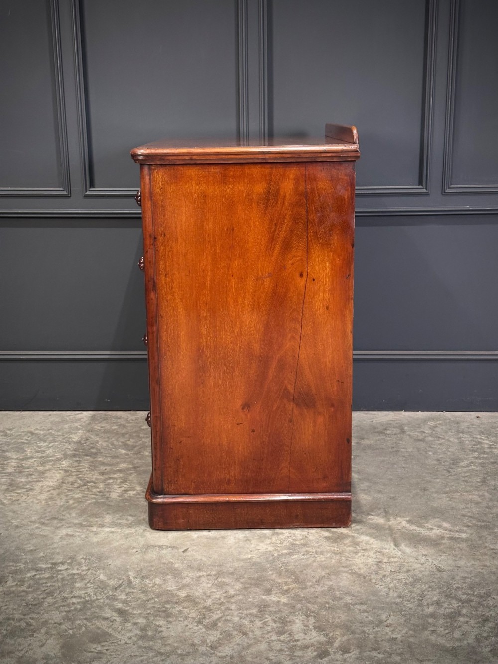 A Victorian flame mahogany chest of drawers featuring two short over three long drawers with turned knobs and a plinth base. View XIII