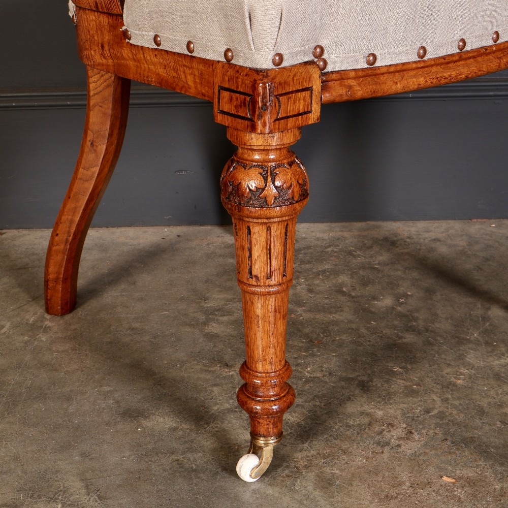 A set of ten Victorian oak dining chairs with rounded hoop backs, neutral fabric seats with stud trim, and carved front legs on ceramic castors. View V