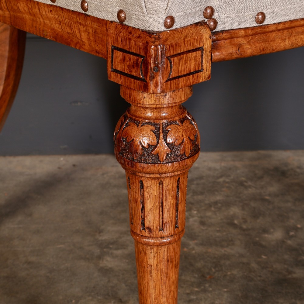 A set of ten Victorian oak dining chairs with rounded hoop backs, neutral fabric seats with stud trim, and carved front legs on ceramic castors. View VI