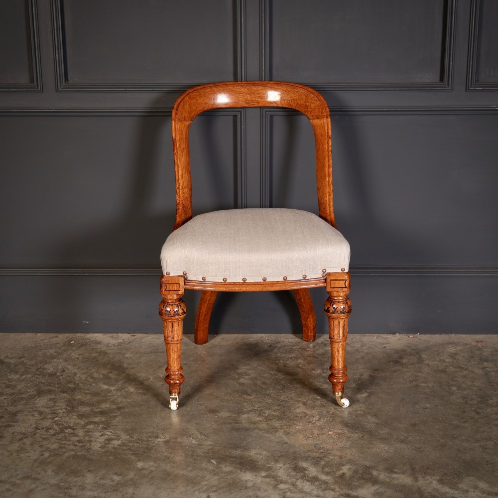A set of ten Victorian oak dining chairs with rounded hoop backs, neutral fabric seats with stud trim, and carved front legs on ceramic castors. View VII