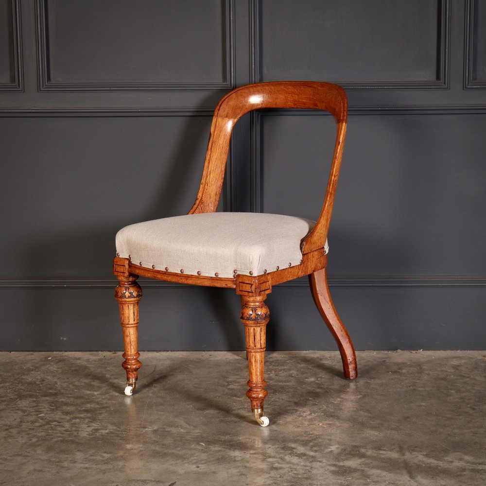 A set of ten Victorian oak dining chairs with rounded hoop backs, neutral fabric seats with stud trim, and carved front legs on ceramic castors. View VIII