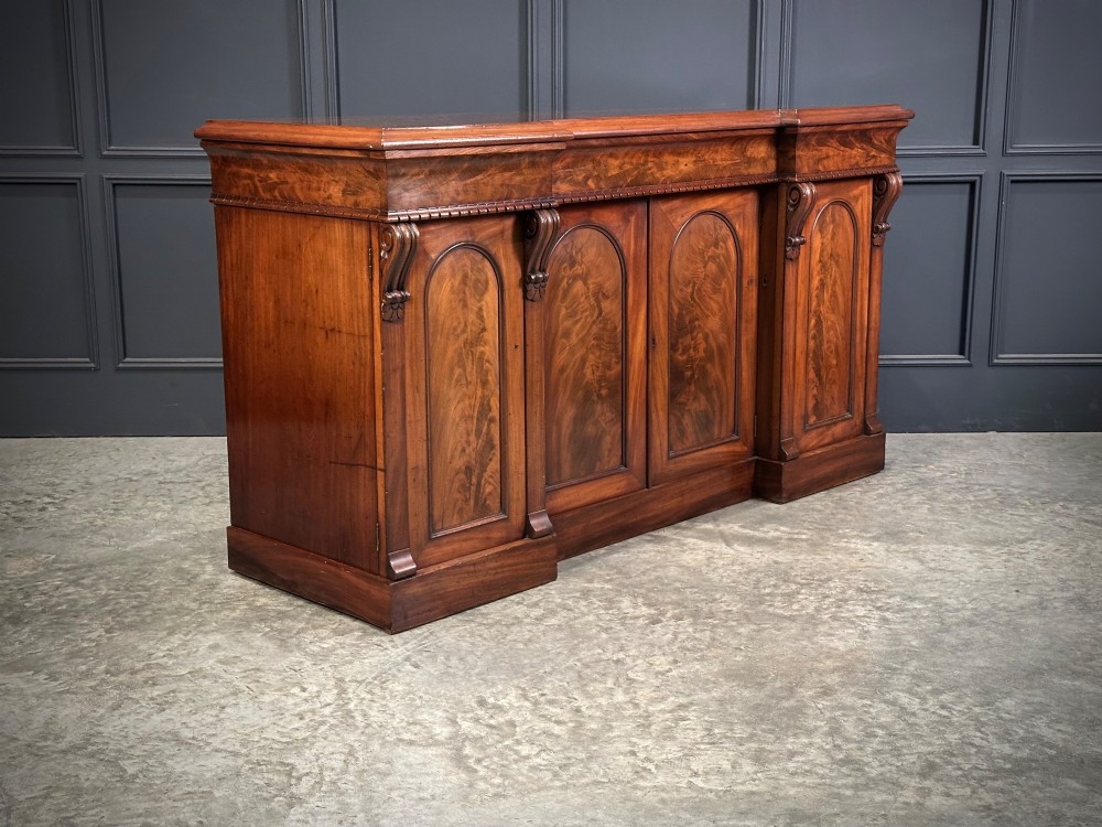 A Victorian flame mahogany four-door sideboard featuring arched panel doors, hand-carved corbel brackets, and a flat plinth base. View II