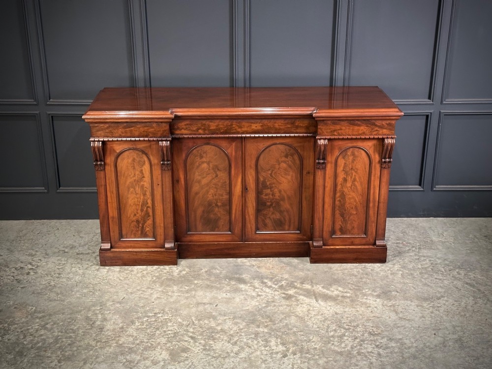 A Victorian flame mahogany four-door sideboard featuring arched panel doors, hand-carved corbel brackets, and a flat plinth base. View III