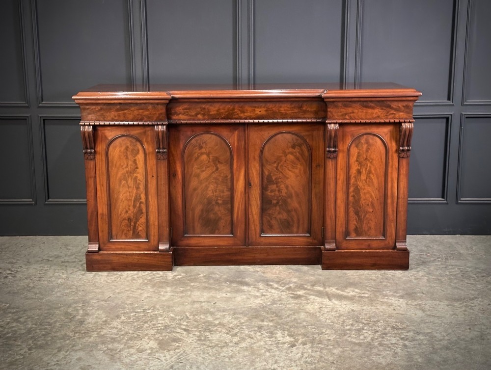 A Victorian flame mahogany four-door sideboard featuring arched panel doors, hand-carved corbel brackets, and a flat plinth base. View IV
