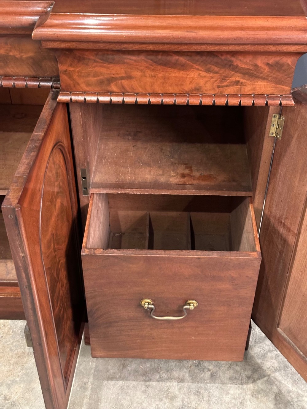 A Victorian flame mahogany four-door sideboard featuring arched panel doors, hand-carved corbel brackets, and a flat plinth base. View VI
