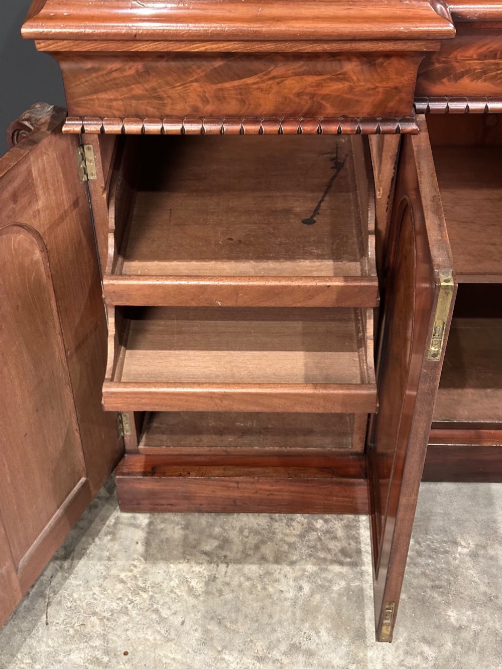 A Victorian flame mahogany four-door sideboard featuring arched panel doors, hand-carved corbel brackets, and a flat plinth base. View VII
