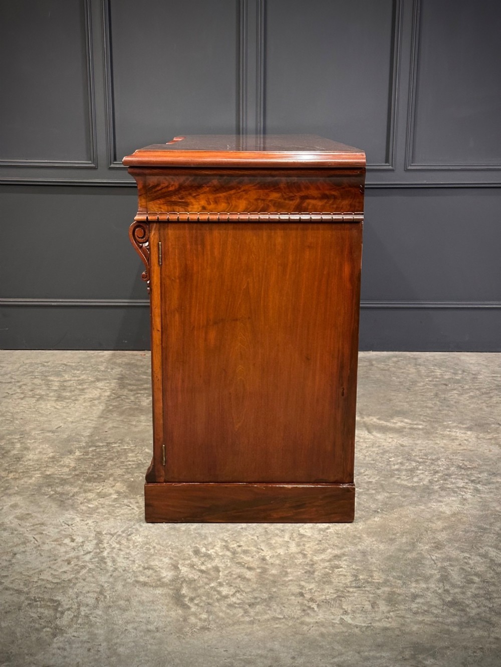 A Victorian flame mahogany four-door sideboard featuring arched panel doors, hand-carved corbel brackets, and a flat plinth base. View XII