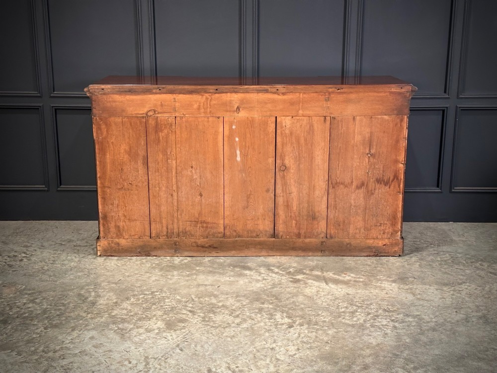 A Victorian flame mahogany four-door sideboard featuring arched panel doors, hand-carved corbel brackets, and a flat plinth base. View XIII
