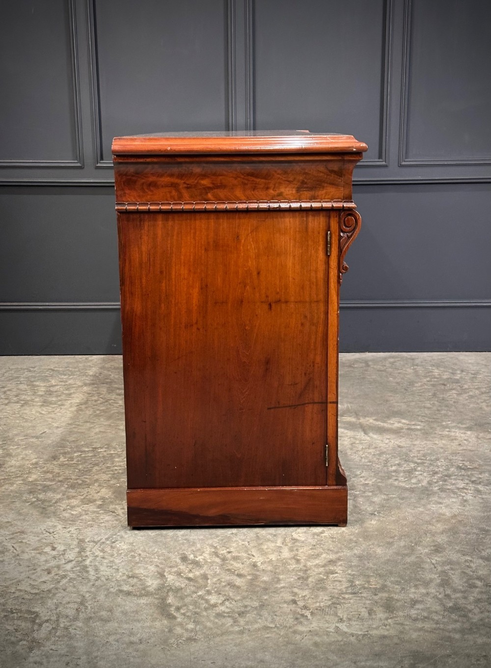 A Victorian flame mahogany four-door sideboard featuring arched panel doors, hand-carved corbel brackets, and a flat plinth base. View XIV