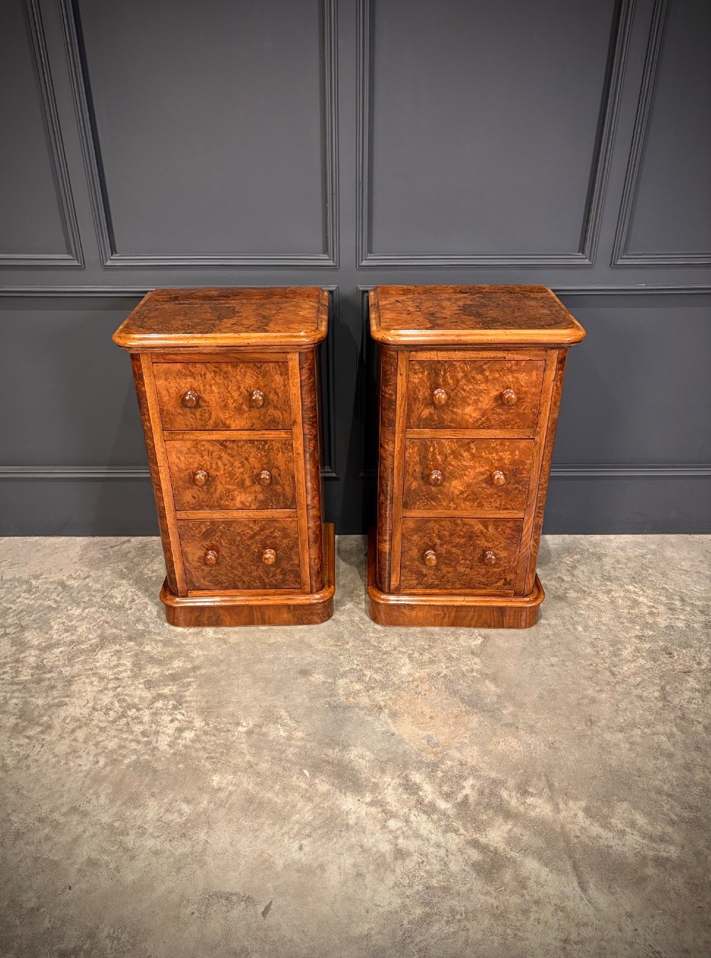 A matching pair of Victorian burr walnut bedside chests featuring three drawers each with turned wooden knobs and rounded plinth bases. View II