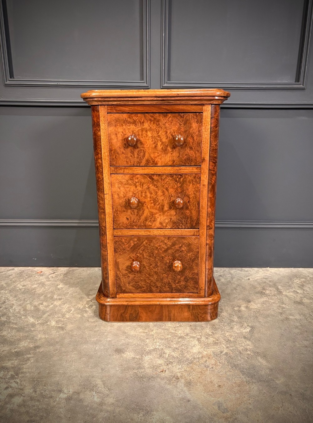 A matching pair of Victorian burr walnut bedside chests featuring three drawers each with turned wooden knobs and rounded plinth bases. View VIII
