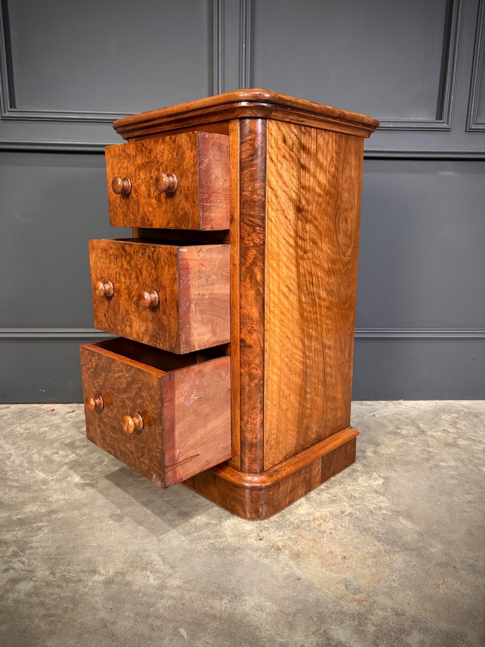 A matching pair of Victorian burr walnut bedside chests featuring three drawers each with turned wooden knobs and rounded plinth bases. View XI