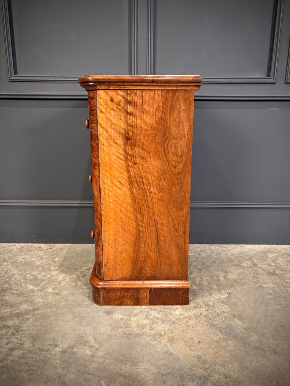 A matching pair of Victorian burr walnut bedside chests featuring three drawers each with turned wooden knobs and rounded plinth bases. View XII