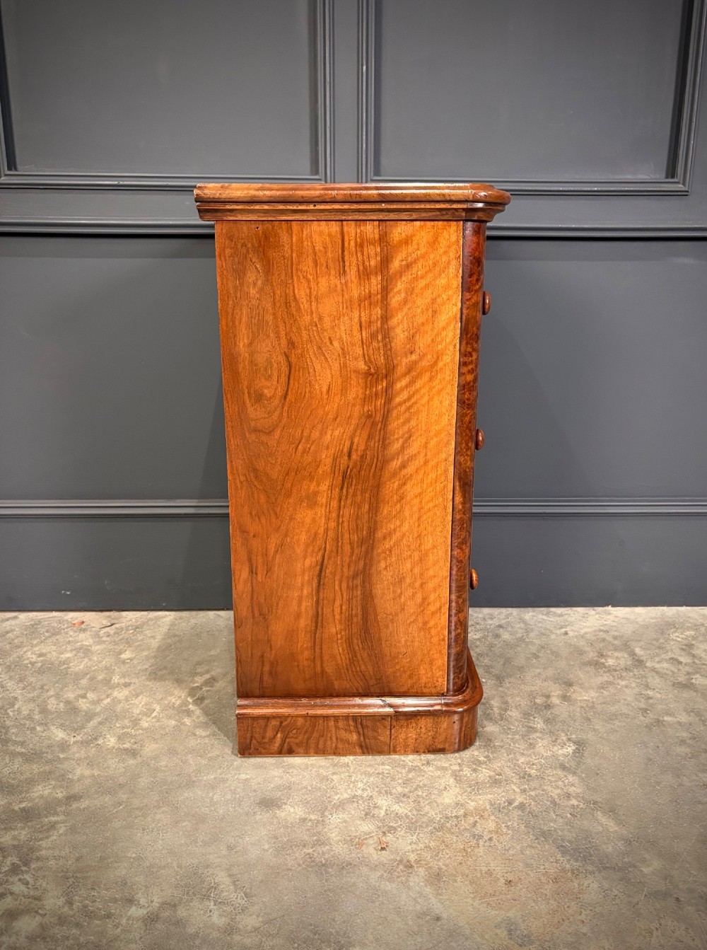 A matching pair of Victorian burr walnut bedside chests featuring three drawers each with turned wooden knobs and rounded plinth bases. View XIV