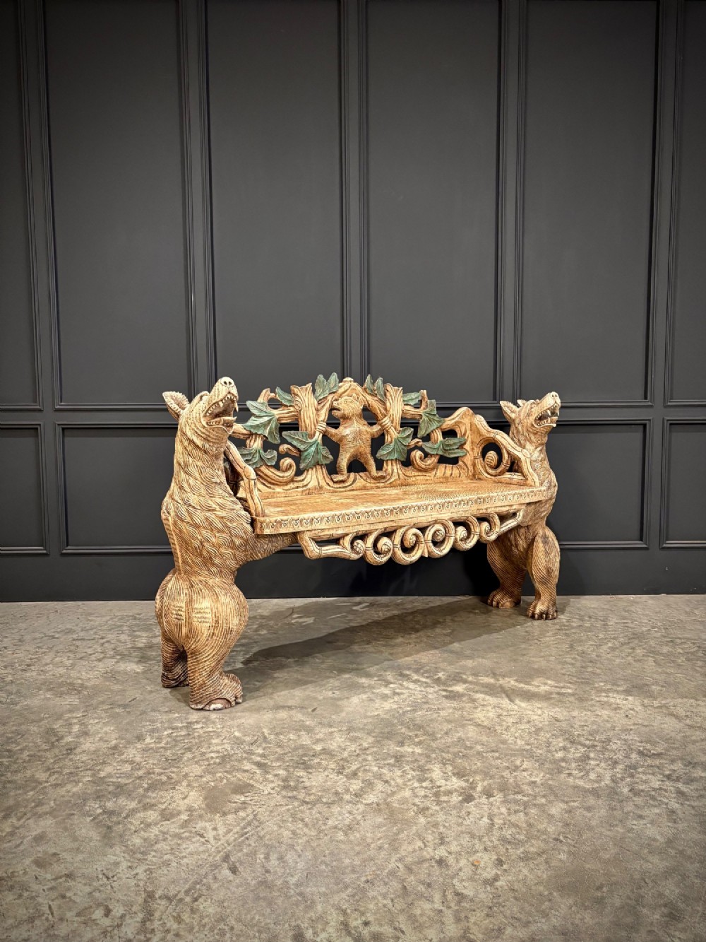 A carved wooden two-seat bench featuring two rearing bears forming the sides and armrests, with scroll motifs and carved green foliage across the backrest.