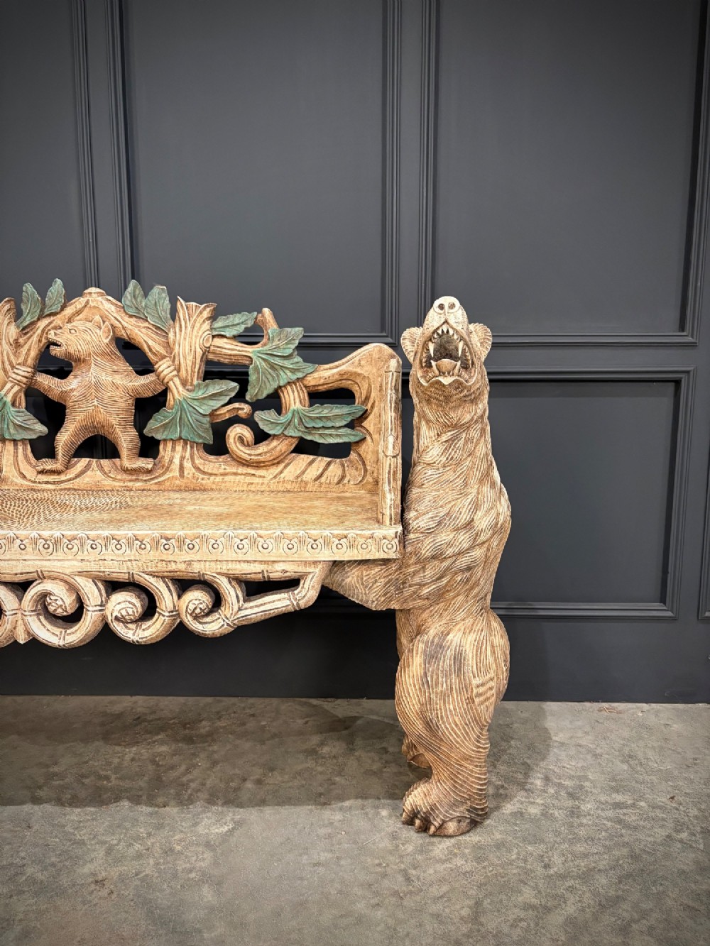 A carved wooden two-seat bench featuring two rearing bears forming the sides and armrests, with scroll motifs and carved green foliage across the backrest. View V