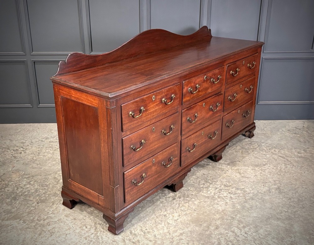 An 18th-century mahogany bank of nine drawers featuring a shaped upstand gallery back, brass swan-neck handles, and bracket feet. View II