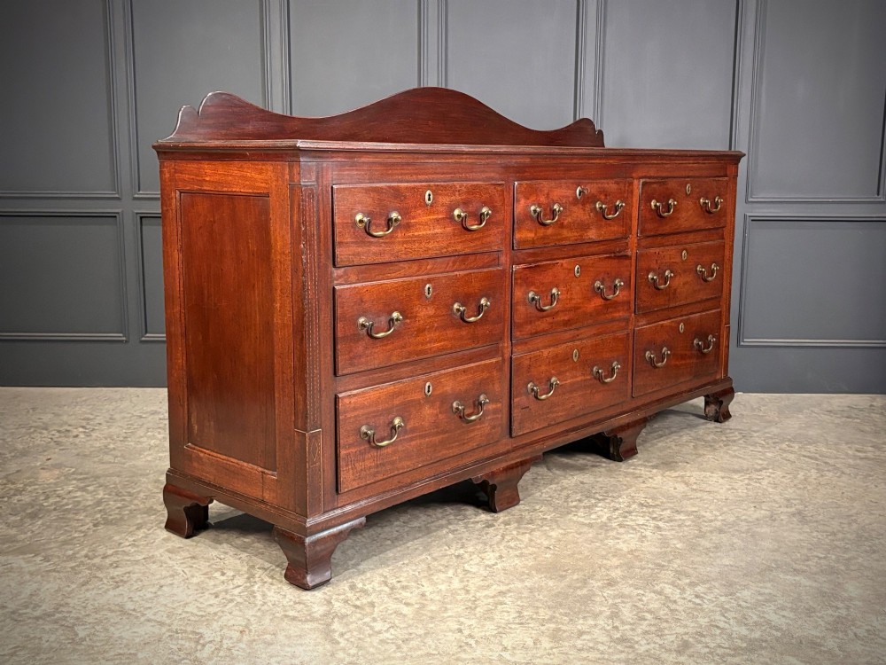 An 18th-century mahogany bank of nine drawers featuring a shaped upstand gallery back, brass swan-neck handles, and bracket feet. View III