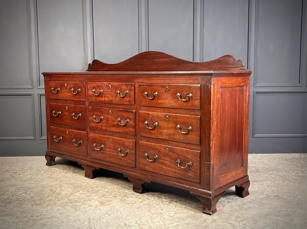 An 18th-century mahogany bank of nine drawers featuring a shaped upstand gallery back, brass swan-neck handles, and bracket feet. View VII