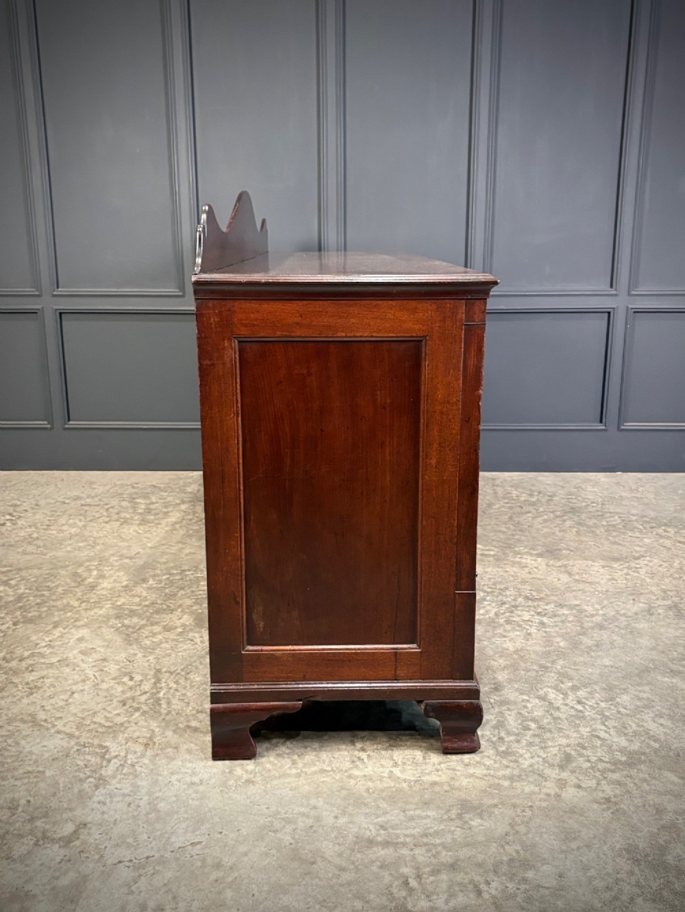 An 18th-century mahogany bank of nine drawers featuring a shaped upstand gallery back, brass swan-neck handles, and bracket feet. View X