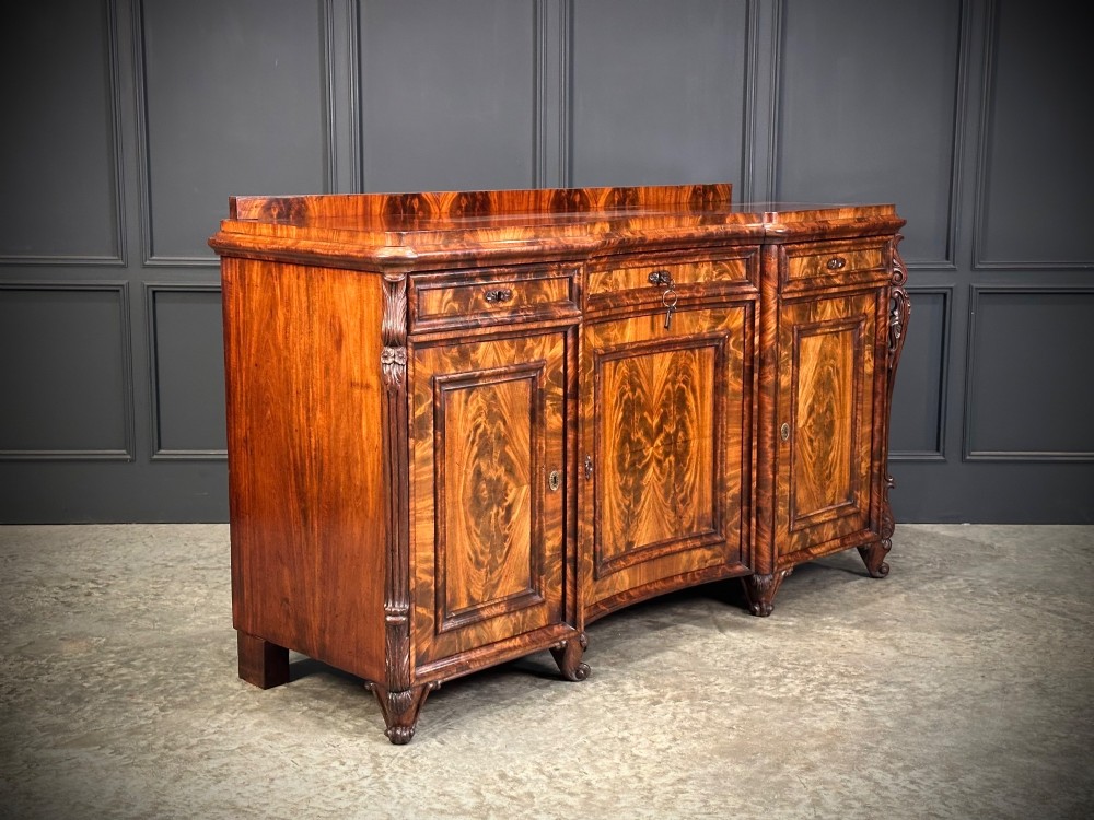 A flame mahogany Biedermeier sideboard featuring three upper drawers over three cupboard doors with symmetrical bookmatched wood grain patterns. View III