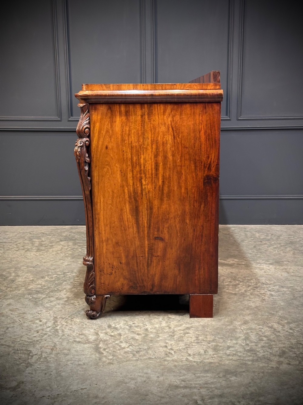 A flame mahogany Biedermeier sideboard featuring three upper drawers over three cupboard doors with symmetrical bookmatched wood grain patterns. View VIII