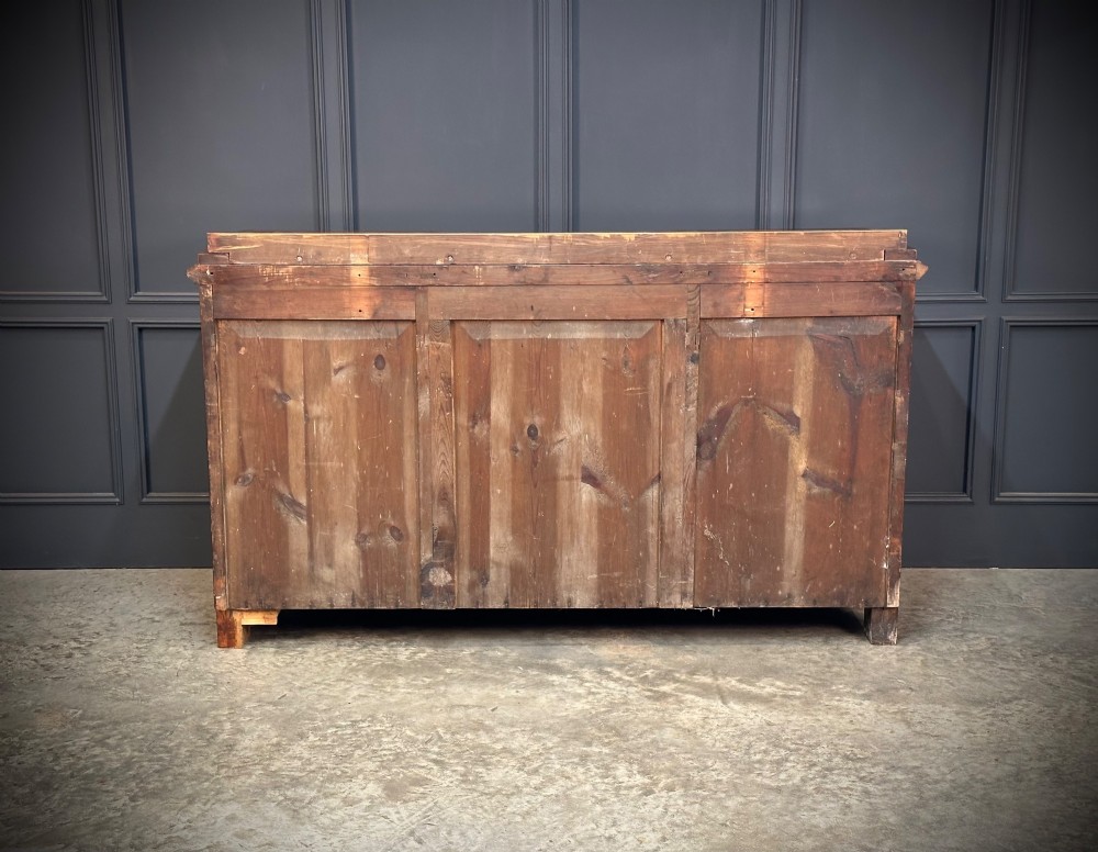 A flame mahogany Biedermeier sideboard featuring three upper drawers over three cupboard doors with symmetrical bookmatched wood grain patterns. View IX