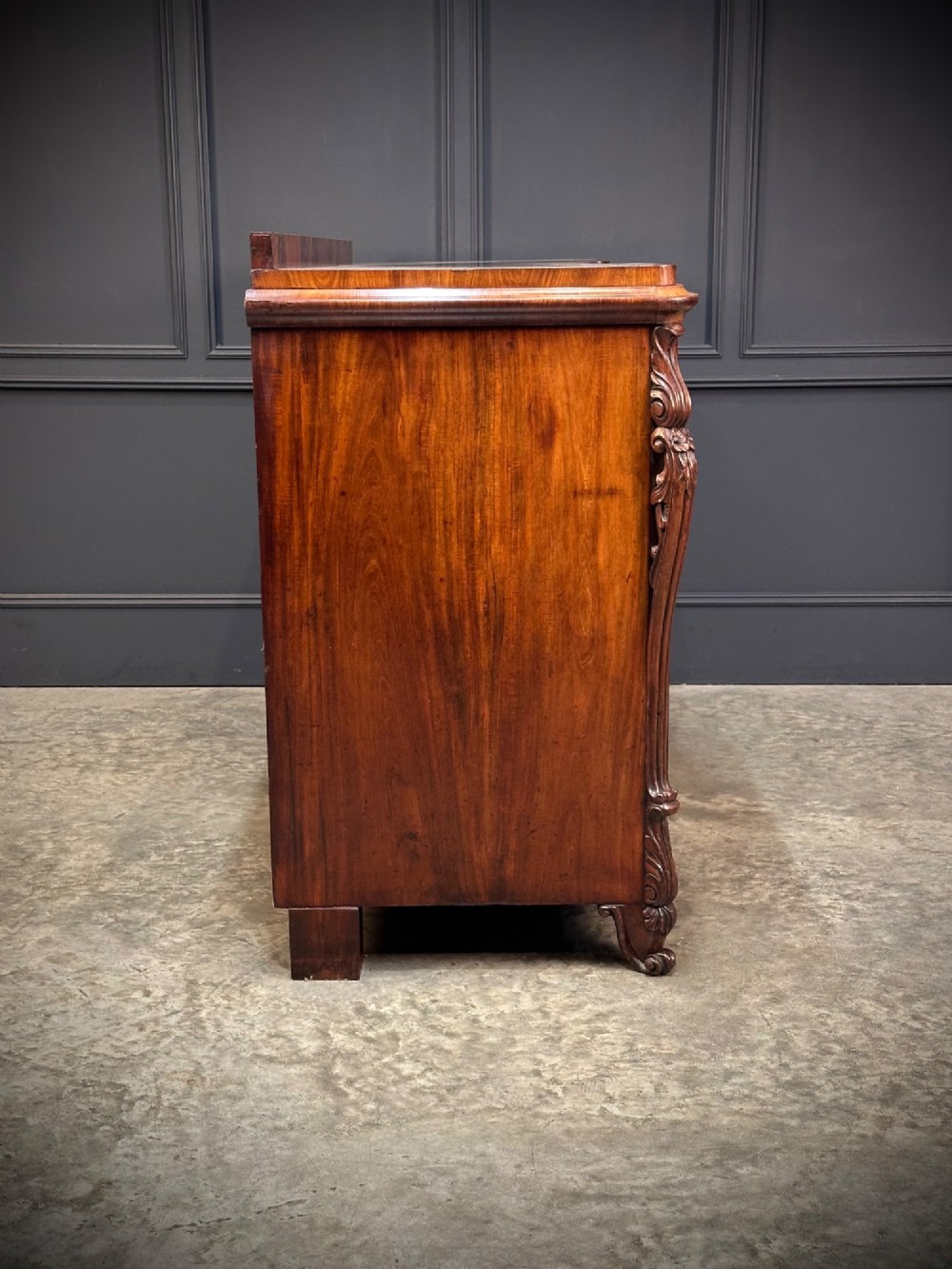 A flame mahogany Biedermeier sideboard featuring three upper drawers over three cupboard doors with symmetrical bookmatched wood grain patterns. View X