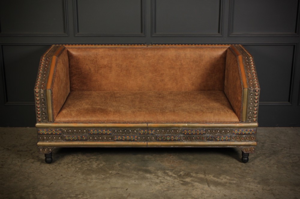 A boxy Moroccan-style sofa featuring tan leather upholstery on the seat and interior, surrounded by an exterior clad in embossed brass metal panels with decorative studding. View III