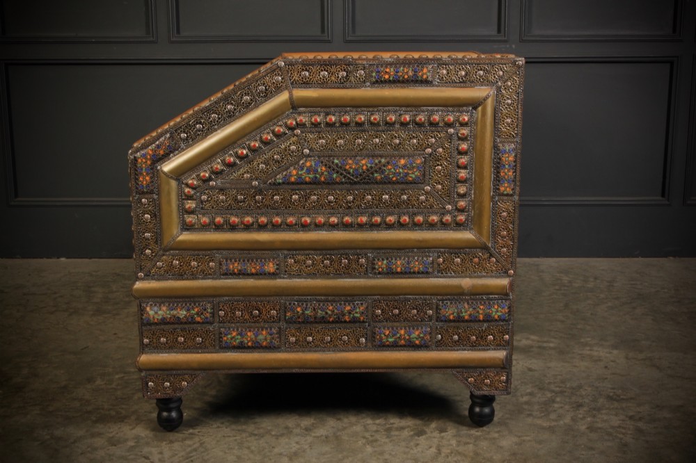 A boxy Moroccan-style sofa featuring tan leather upholstery on the seat and interior, surrounded by an exterior clad in embossed brass metal panels with decorative studding. View VIII
