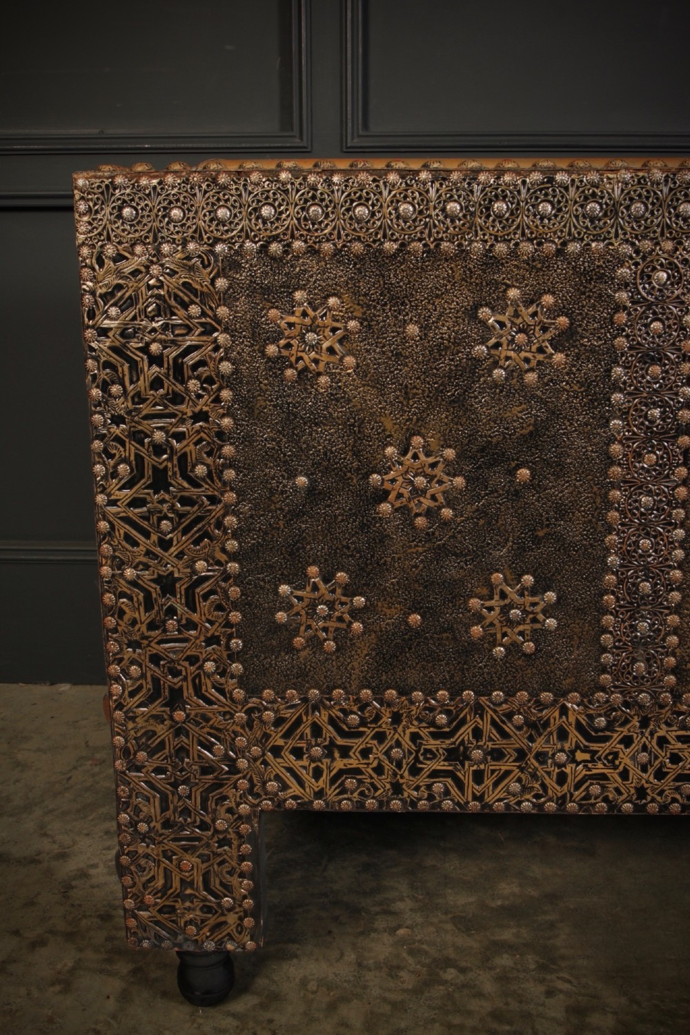 A boxy Moroccan-style sofa featuring tan leather upholstery on the seat and interior, surrounded by an exterior clad in embossed brass metal panels with decorative studding. View X