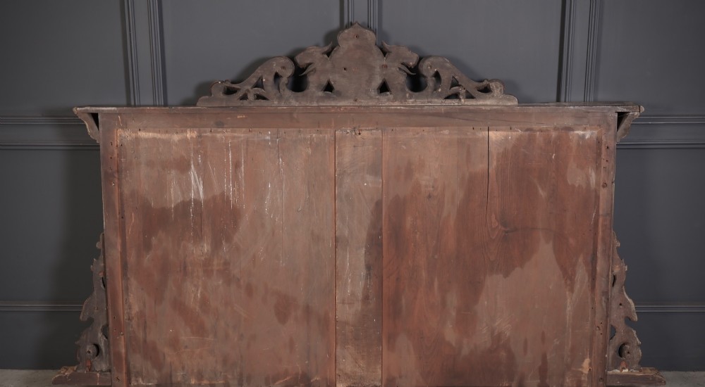 A wide Victorian oak overmantel mirror featuring detailed hand-carved cresting with beast heads, side pilasters with fruit swags, and carved human masks. View IV
