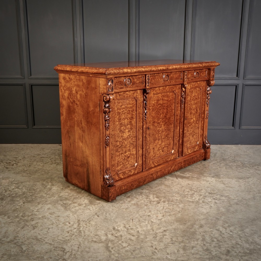 A 19th-century Victorian pollard oak sideboard featuring three relief-panelled cupboard doors, carved corbels, and a figure-rich timber surface. View III