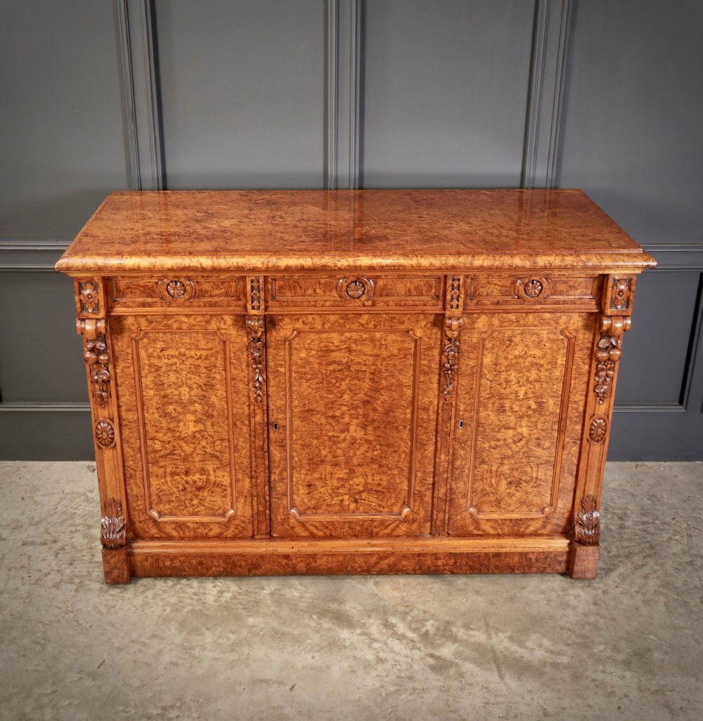 A 19th-century Victorian pollard oak sideboard featuring three relief-panelled cupboard doors, carved corbels, and a figure-rich timber surface. View V