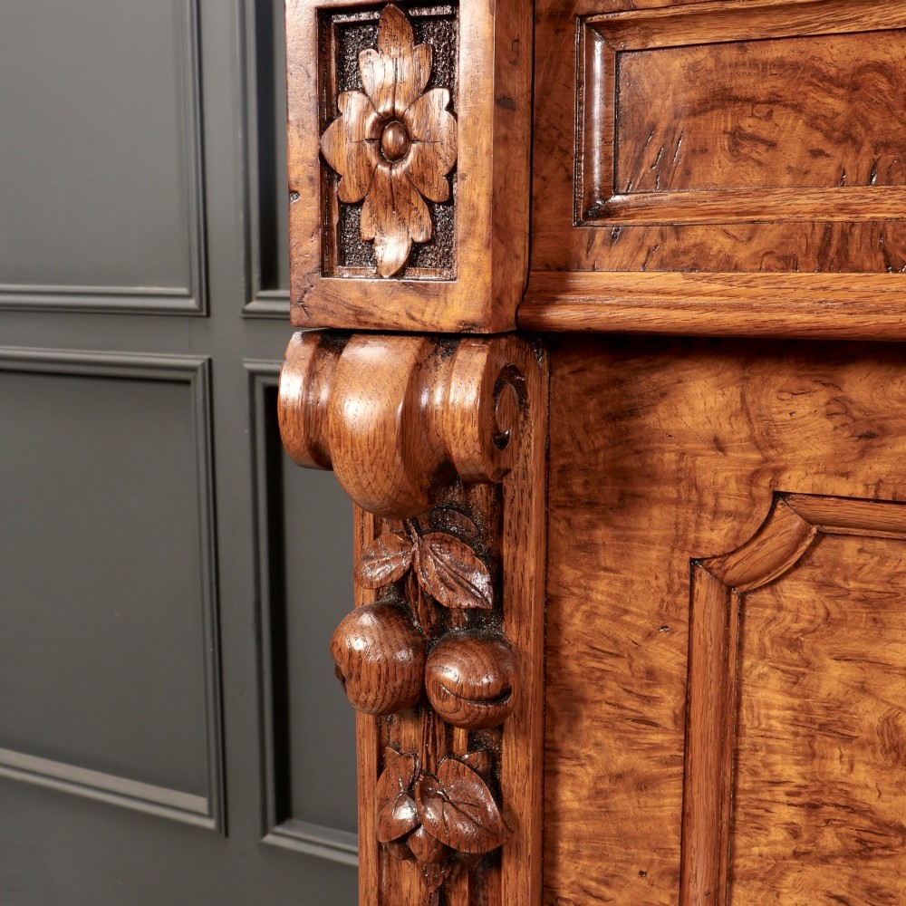 A 19th-century Victorian pollard oak sideboard featuring three relief-panelled cupboard doors, carved corbels, and a figure-rich timber surface. View VIII