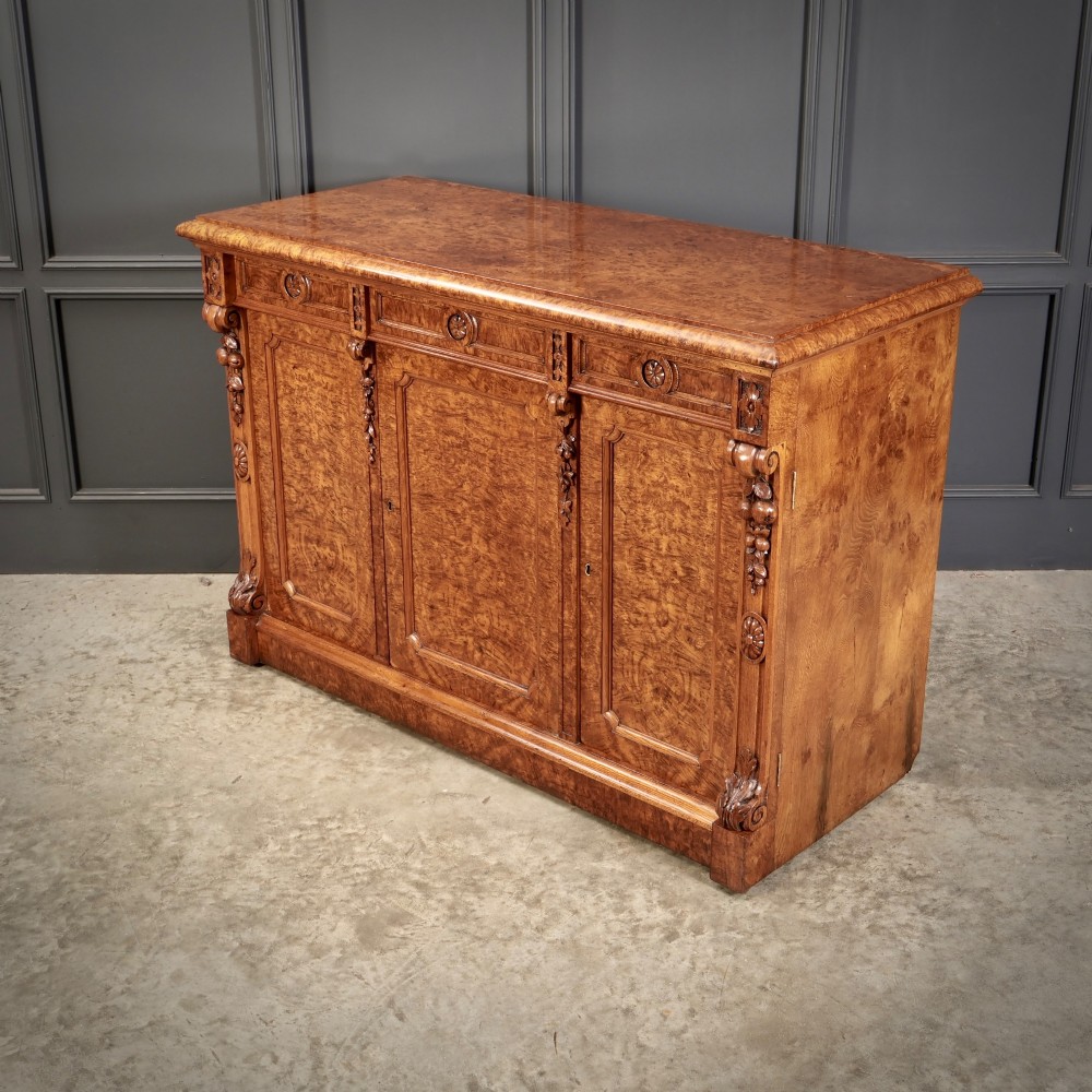 A 19th-century Victorian pollard oak sideboard featuring three relief-panelled cupboard doors, carved corbels, and a figure-rich timber surface.