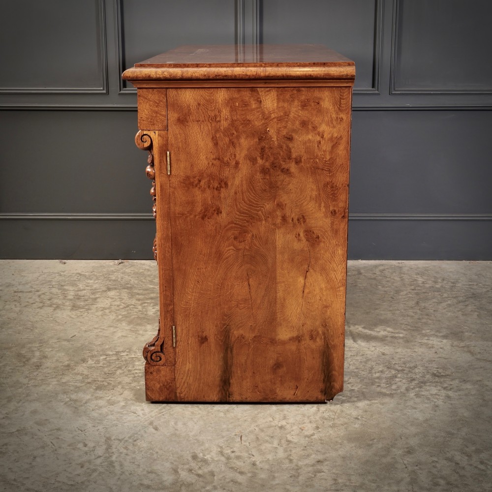 A 19th-century Victorian pollard oak sideboard featuring three relief-panelled cupboard doors, carved corbels, and a figure-rich timber surface. View XIII