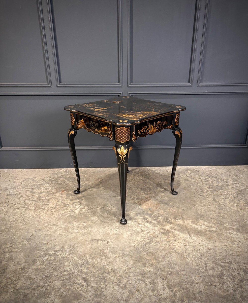 A black lacquered square occasional table featuring gilded Chinoiserie landscape scenes, shaped apron edges, a single drawer, and slender cabriole legs. View II