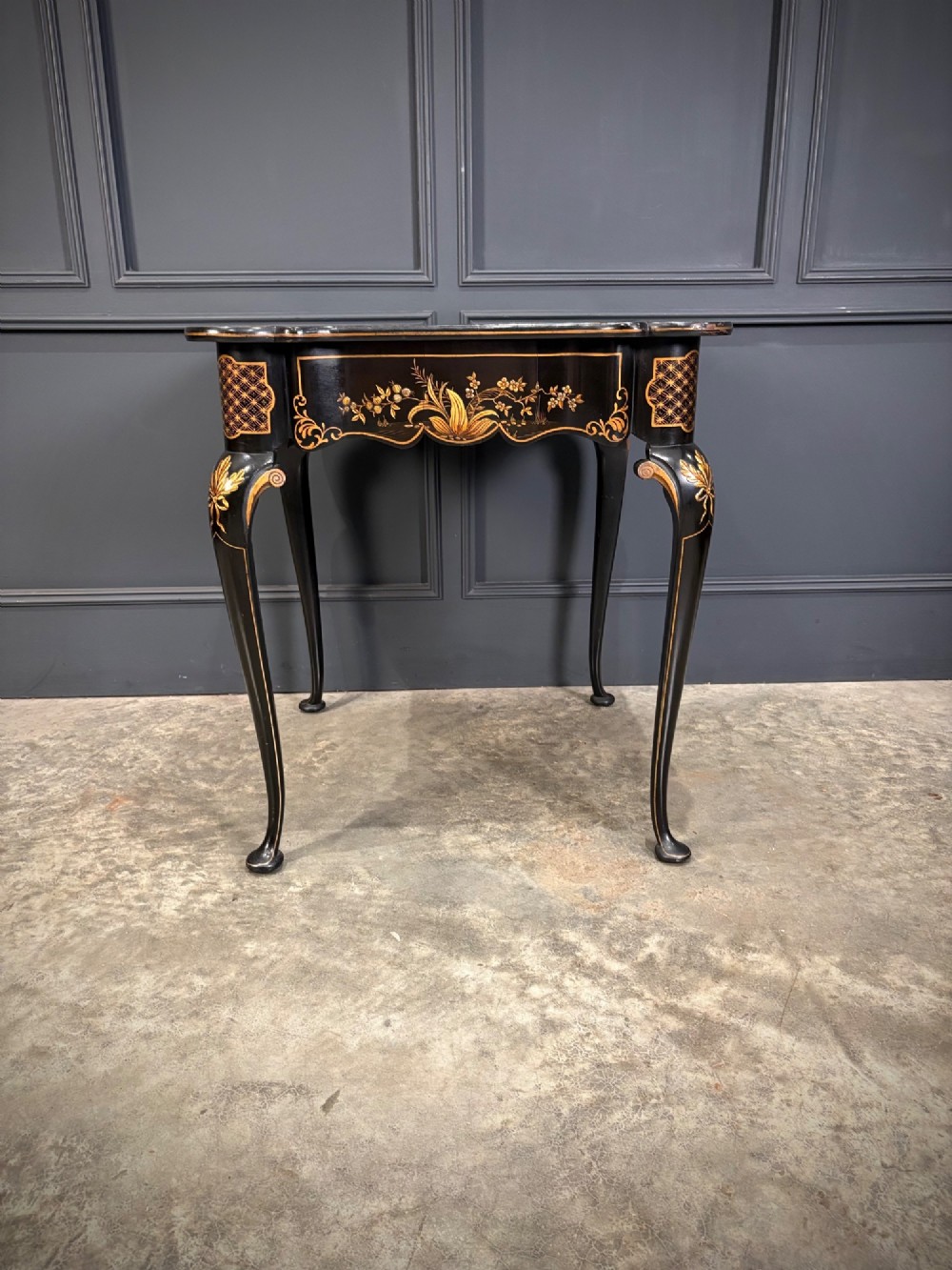 A black lacquered square occasional table featuring gilded Chinoiserie landscape scenes, shaped apron edges, a single drawer, and slender cabriole legs. View IX