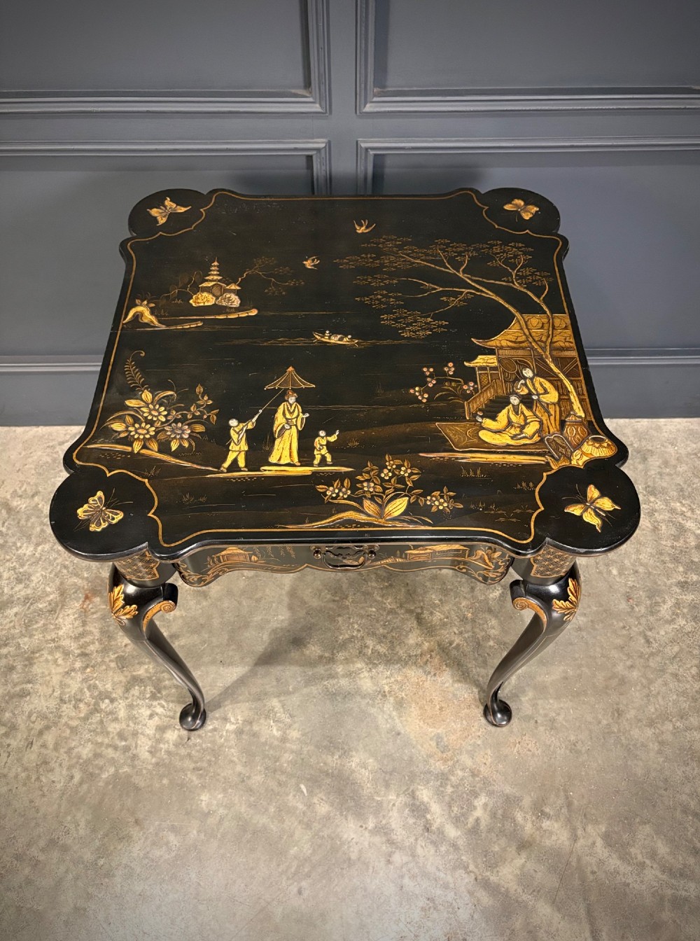 A black lacquered square occasional table featuring gilded Chinoiserie landscape scenes, shaped apron edges, a single drawer, and slender cabriole legs. View XII