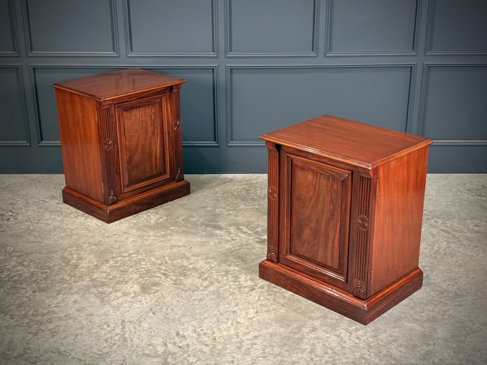 A matching pair of Victorian mahogany bedside cabinets featuring panelled doors with flame veneer and carved fluted pilasters on plinth bases. View III