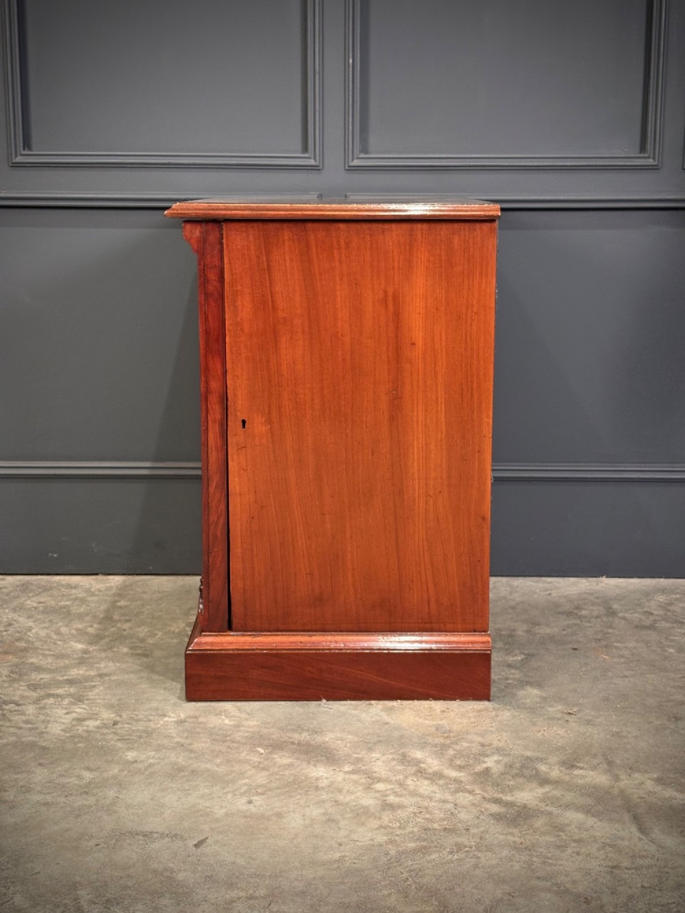 A matching pair of Victorian mahogany bedside cabinets featuring panelled doors with flame veneer and carved fluted pilasters on plinth bases. View IX