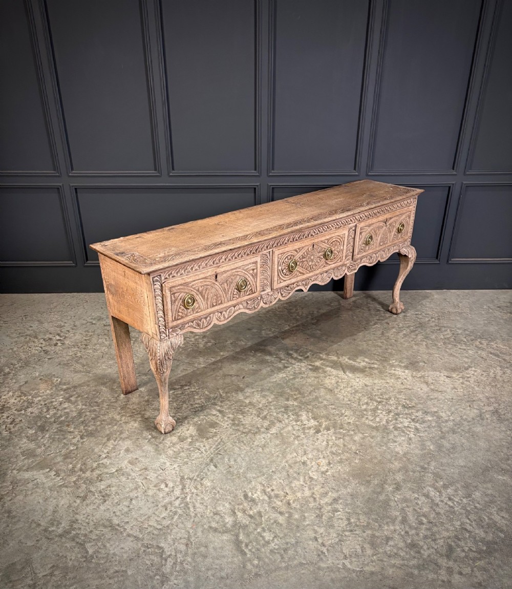 An 18th-century carved oak dresser base with three carved drawer fronts, a decorative apron, cabriole front legs, and claw and ball feet. View II