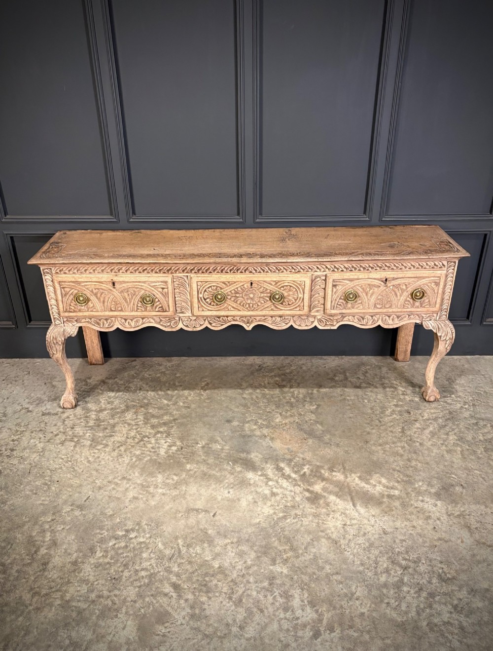 An 18th-century carved oak dresser base with three carved drawer fronts, a decorative apron, cabriole front legs, and claw and ball feet. View III