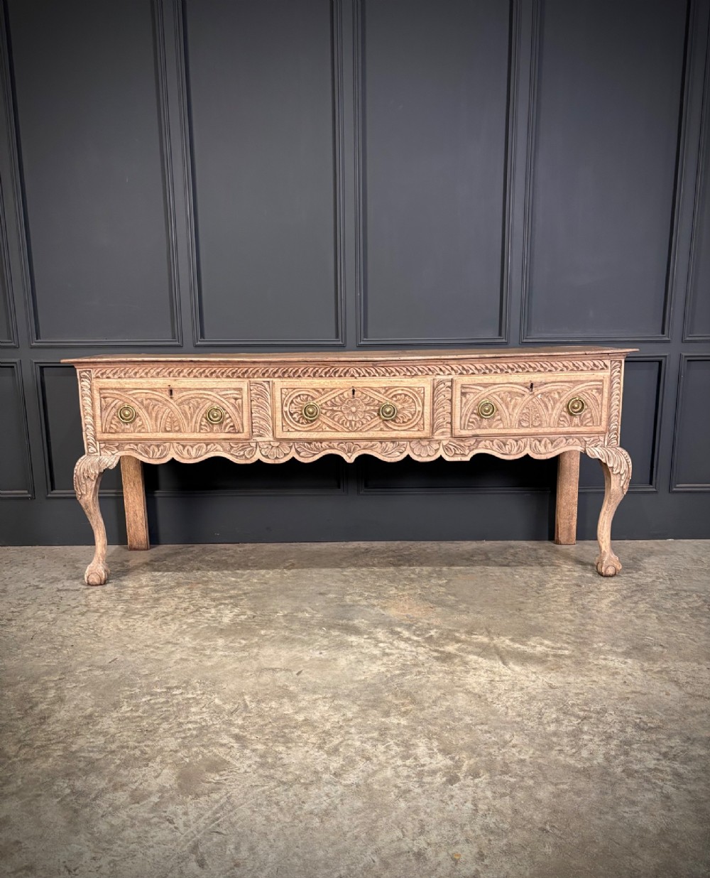 An 18th-century carved oak dresser base with three carved drawer fronts, a decorative apron, cabriole front legs, and claw and ball feet. View IV