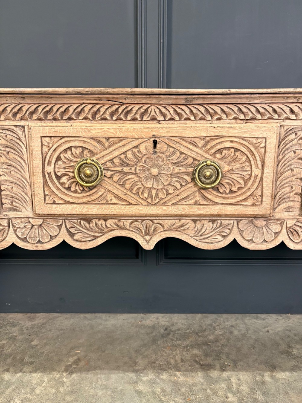An 18th-century carved oak dresser base with three carved drawer fronts, a decorative apron, cabriole front legs, and claw and ball feet. View V
