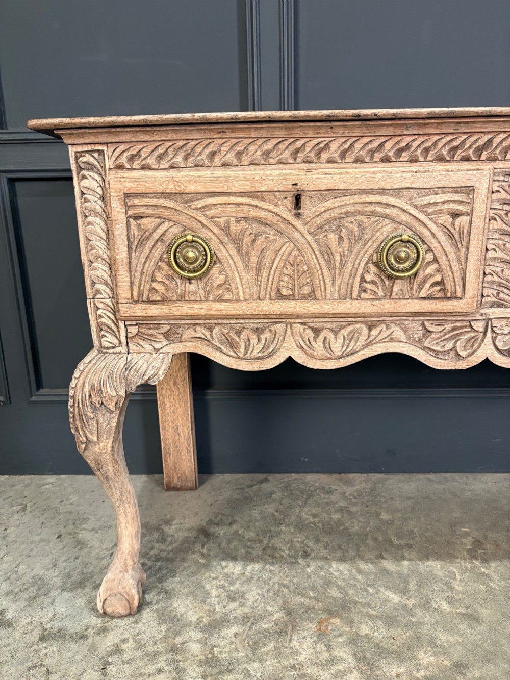 An 18th-century carved oak dresser base with three carved drawer fronts, a decorative apron, cabriole front legs, and claw and ball feet. View VI